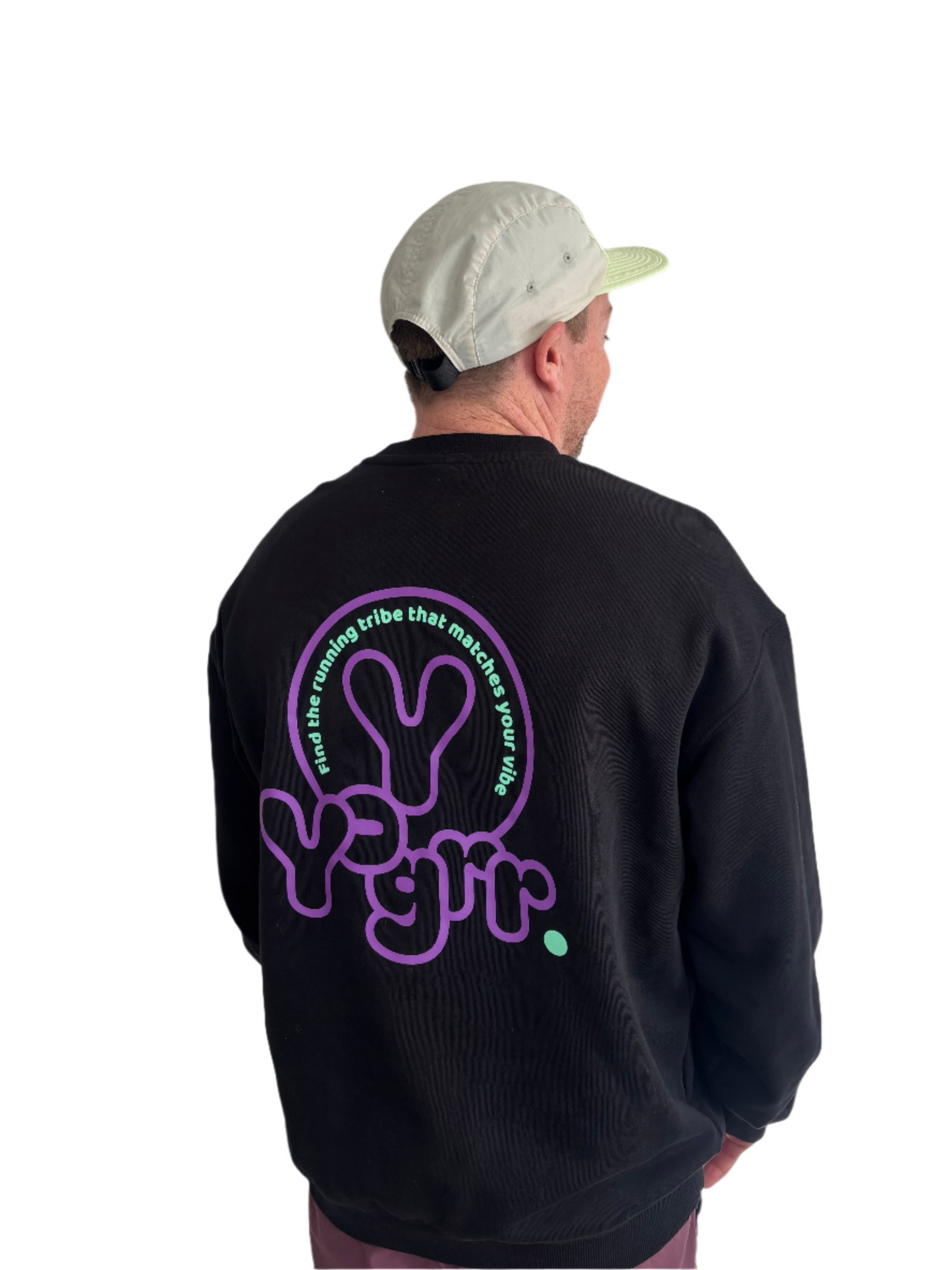 Person wearing a black sweatshirt with a purple graphic on the back against a white wall.