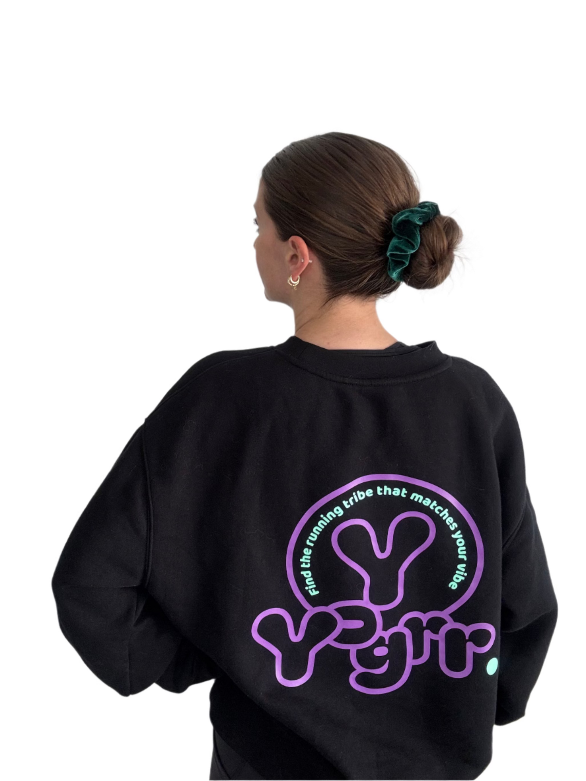 Person wearing a black sweatshirt with a purple logo on the back against a white wall